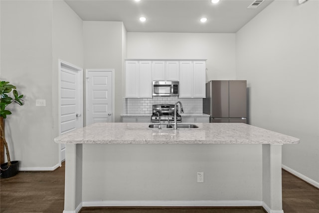 kitchen featuring white cabinets, appliances with stainless steel finishes, a kitchen island with sink, and sink