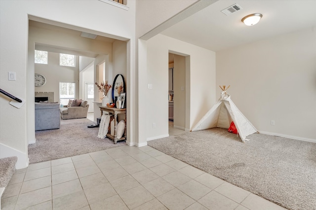 interior space featuring a tiled fireplace and light carpet