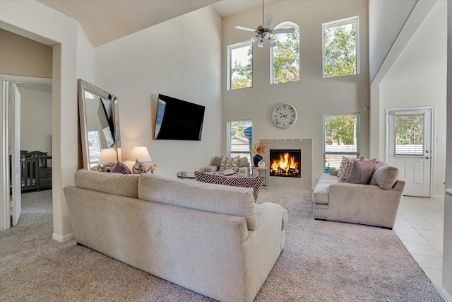 living room with a tiled fireplace, ceiling fan, and plenty of natural light