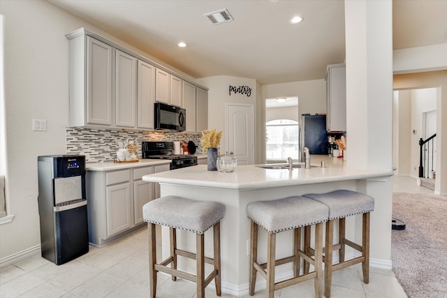 kitchen with backsplash, kitchen peninsula, gray cabinets, black appliances, and sink