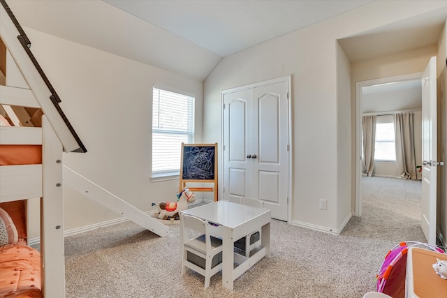 playroom with vaulted ceiling, light colored carpet, and a healthy amount of sunlight