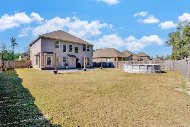 rear view of house with a lawn, a fenced in pool, and a patio area