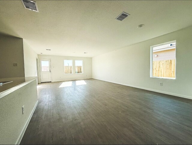 105 Nicholas Rd, Wharton, TX 77488 - unfurnished living room featuring dark wood-style flooring, baseboards, and a textured ceiling