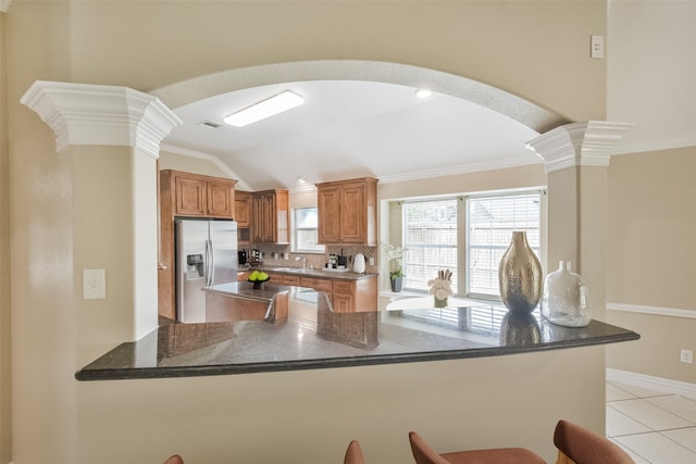 kitchen with stainless steel fridge, kitchen peninsula, vaulted ceiling, and tasteful backsplash