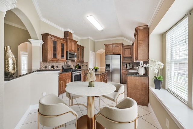 kitchen with appliances with stainless steel finishes, decorative backsplash, light tile patterned floors, and ornate columns