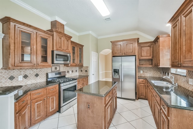 kitchen with tasteful backsplash, sink, a kitchen island, stainless steel appliances, and light tile patterned floors