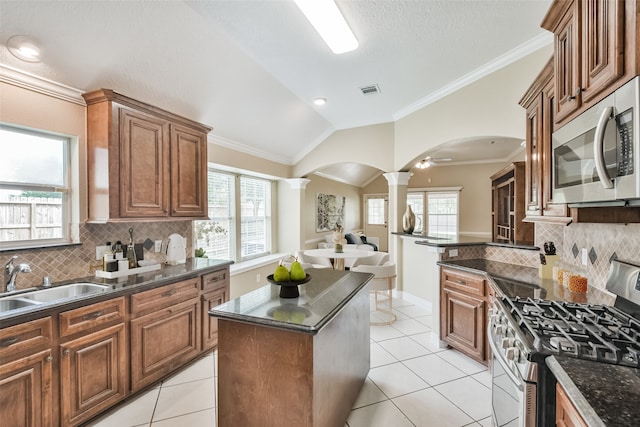 kitchen featuring crown molding, vaulted ceiling, stainless steel appliances, and ornate columns