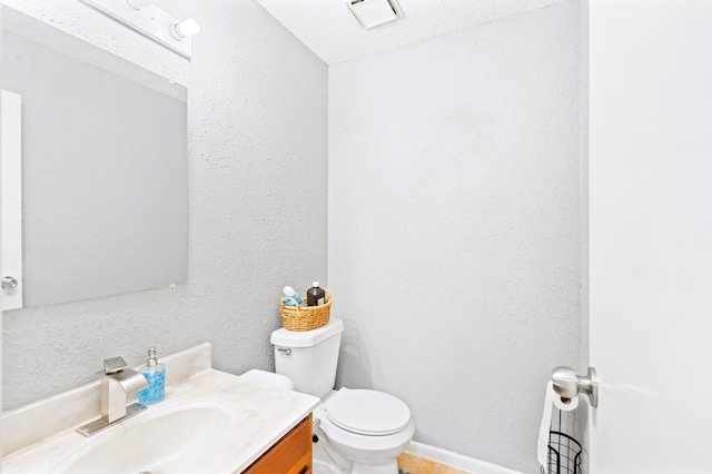 bathroom with vanity, toilet, and a textured ceiling