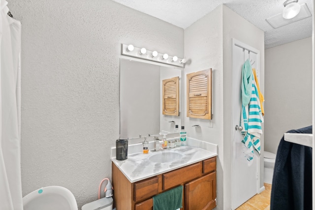 bathroom with tile patterned flooring, a textured ceiling, vanity, and toilet