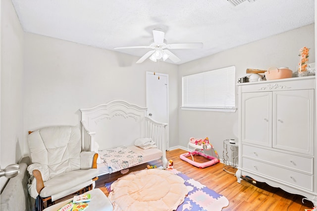 bedroom with a textured ceiling, hardwood / wood-style floors, and ceiling fan