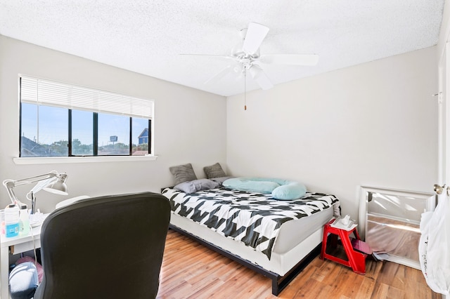 bedroom featuring a textured ceiling, wood-type flooring, and ceiling fan