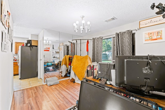 office area with light hardwood / wood-style flooring, a chandelier, and a textured ceiling