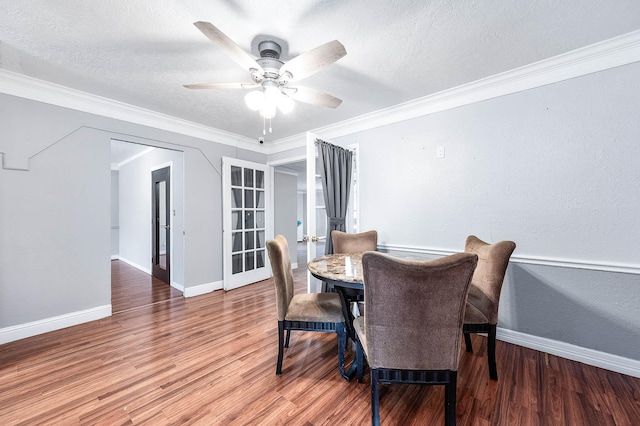 dining room featuring baseboards, a ceiling fan, wood finished floors, and a textured ceiling
