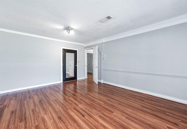 unfurnished room featuring a textured ceiling, ornamental molding, visible vents, wood finished floors, and baseboards