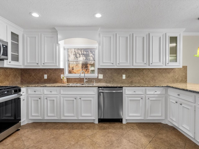 kitchen with stainless steel appliances, white cabinetry, tasteful backsplash, and sink