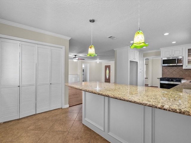 kitchen featuring white cabinets, decorative light fixtures, light stone countertops, and stainless steel appliances