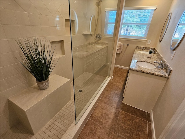 bathroom with tiled shower, vanity, and tile patterned flooring