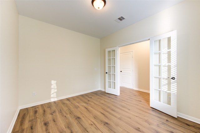 empty room featuring french doors and light hardwood / wood-style floors