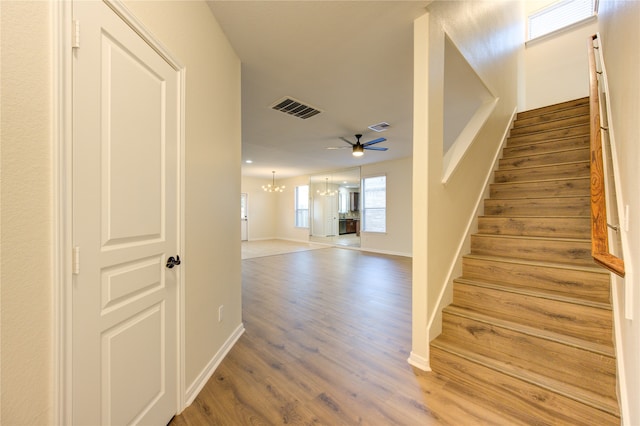 staircase featuring ceiling fan with notable chandelier and wood-type flooring