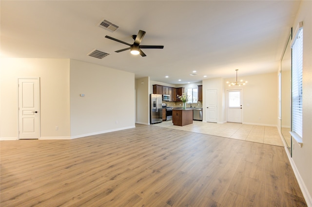 unfurnished living room featuring light wood-type flooring, ceiling fan with notable chandelier, and sink