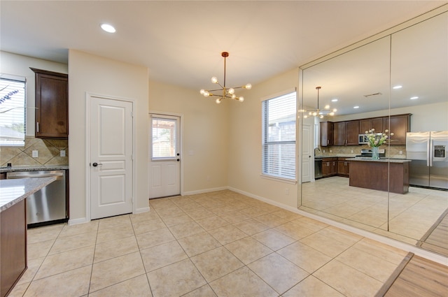 kitchen with decorative light fixtures, decorative backsplash, light tile patterned floors, and stainless steel appliances