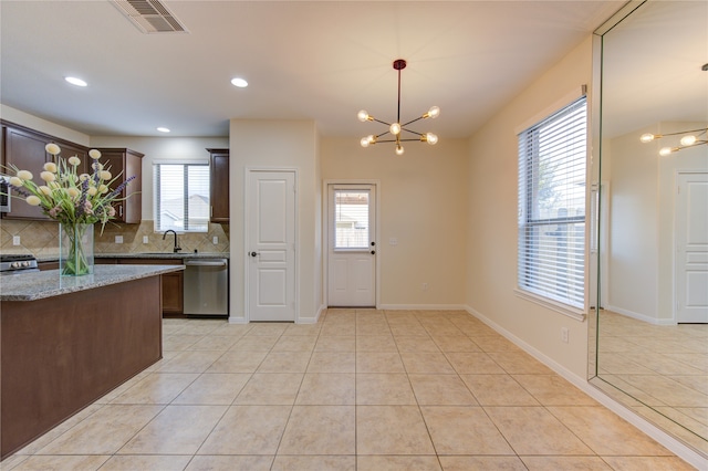 kitchen featuring light tile patterned floors, a chandelier, backsplash, light stone countertops, and appliances with stainless steel finishes