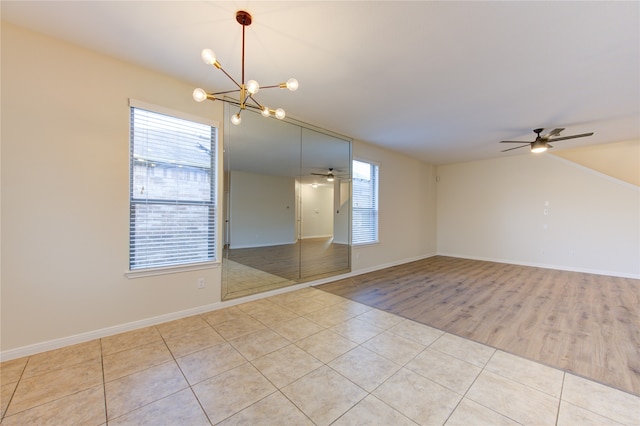 spare room featuring light wood-type flooring and ceiling fan with notable chandelier