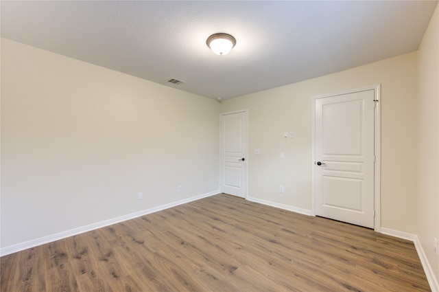 empty room with hardwood / wood-style floors and a textured ceiling