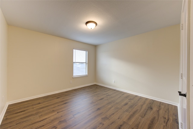 unfurnished room with dark hardwood / wood-style flooring and a textured ceiling