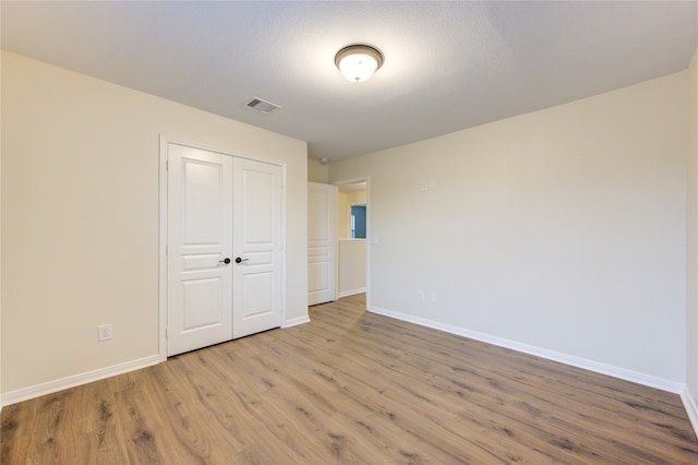 unfurnished bedroom featuring a textured ceiling, a closet, and light hardwood / wood-style flooring