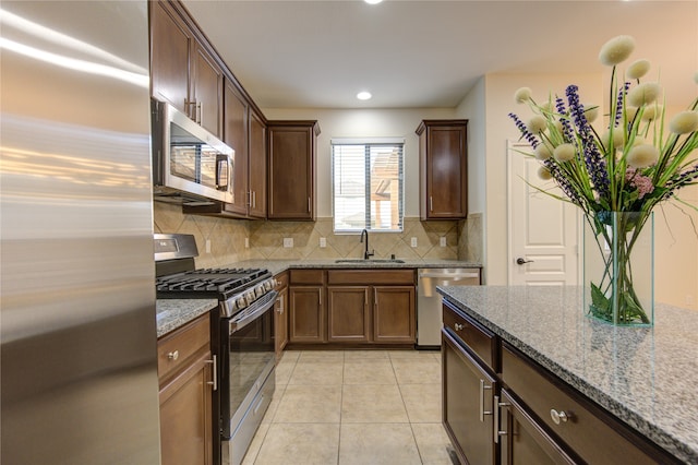 kitchen featuring light tile patterned floors, sink, backsplash, light stone countertops, and appliances with stainless steel finishes