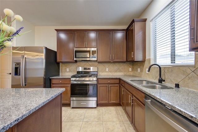 kitchen with light tile patterned floors, sink, backsplash, and appliances with stainless steel finishes