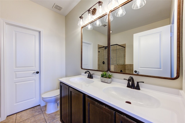 bathroom with toilet, a tile shower, vanity, and tile patterned floors