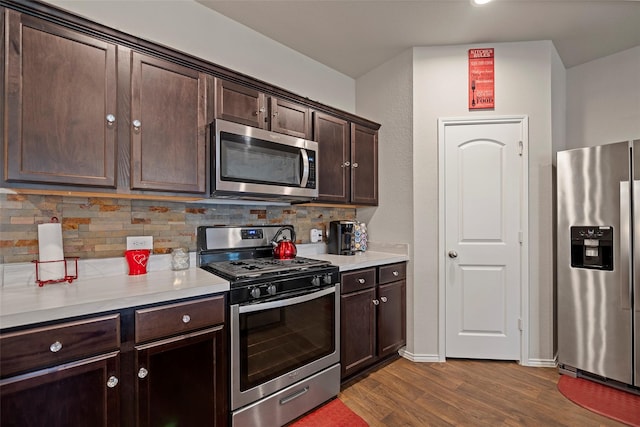 kitchen with dark brown cabinetry, decorative backsplash, stainless steel appliances, and hardwood / wood-style flooring