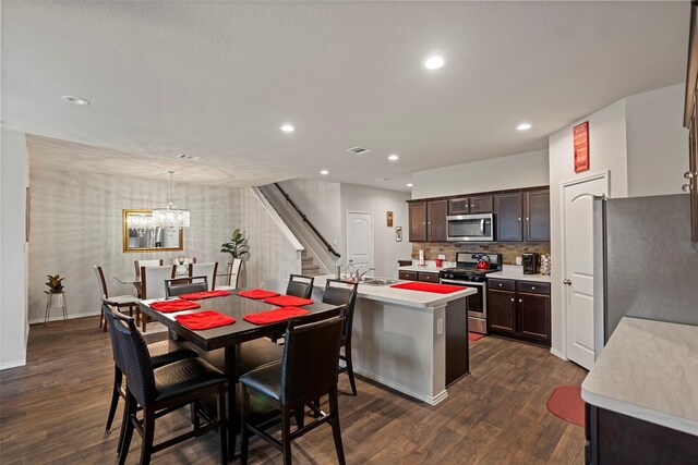 kitchen with pendant lighting, a chandelier, dark hardwood / wood-style floors, appliances with stainless steel finishes, and dark brown cabinetry