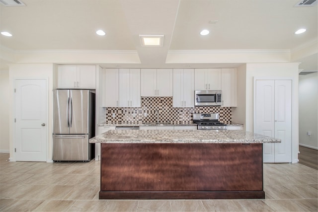 kitchen with white cabinetry, a center island, stainless steel appliances, and light stone counters