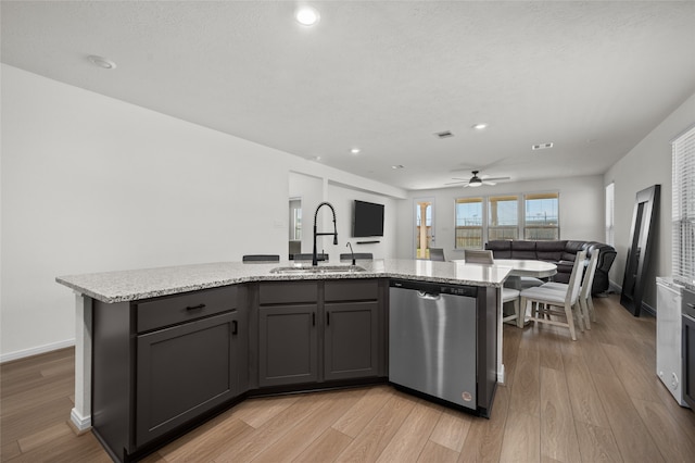 kitchen with stainless steel dishwasher, sink, light hardwood / wood-style flooring, and an island with sink