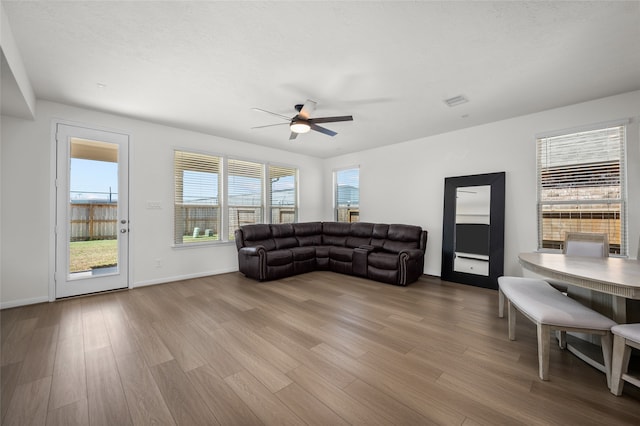 living room with light hardwood / wood-style flooring, ceiling fan, and a textured ceiling