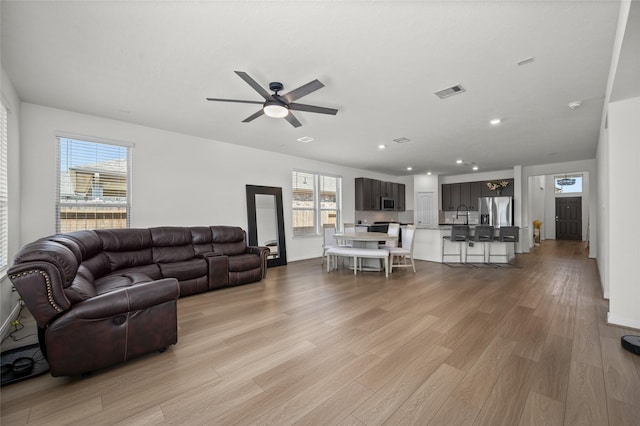 living room with visible vents, ceiling fan, light wood-type flooring, and plenty of natural light