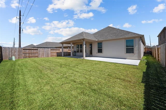 rear view of property featuring roof with shingles, a yard, a patio area, and a fenced backyard