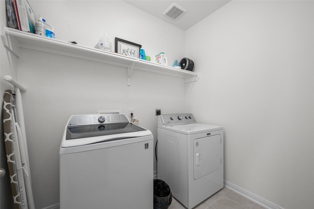 washroom featuring baseboards, light tile patterned floors, visible vents, laundry area, and washing machine and clothes dryer