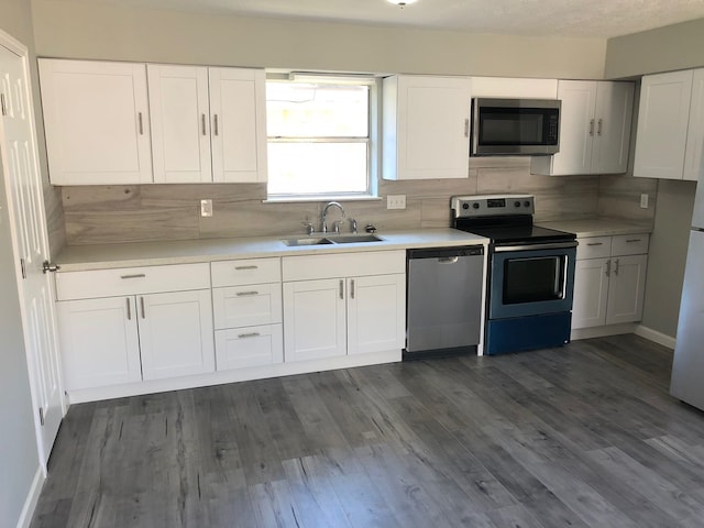 kitchen with appliances with stainless steel finishes, dark hardwood / wood-style floors, and white cabinetry