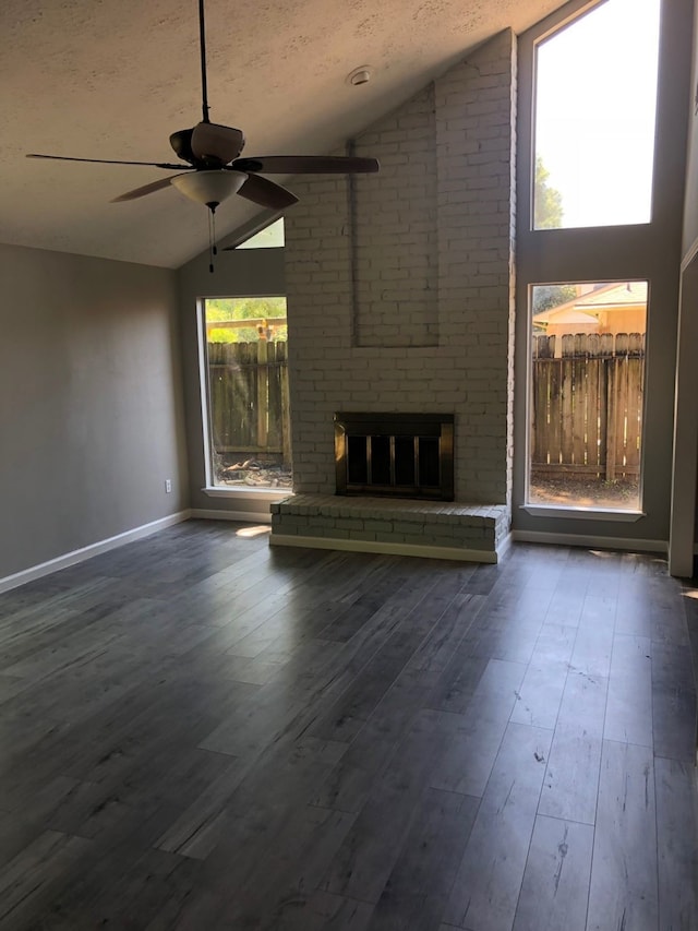 unfurnished living room with a brick fireplace, a textured ceiling, lofted ceiling, ceiling fan, and dark hardwood / wood-style floors