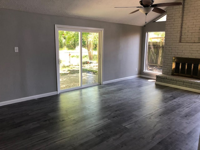 unfurnished living room featuring a textured ceiling, dark hardwood / wood-style floors, lofted ceiling, a fireplace, and ceiling fan