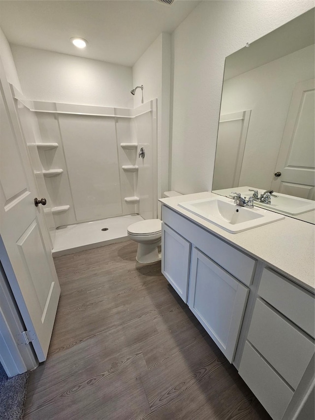 bathroom with hardwood / wood-style flooring, vanity, toilet, and a shower