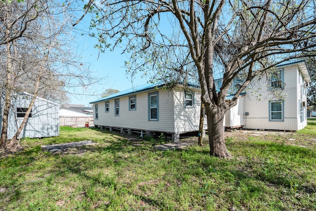 back of property featuring a yard and a storage unit