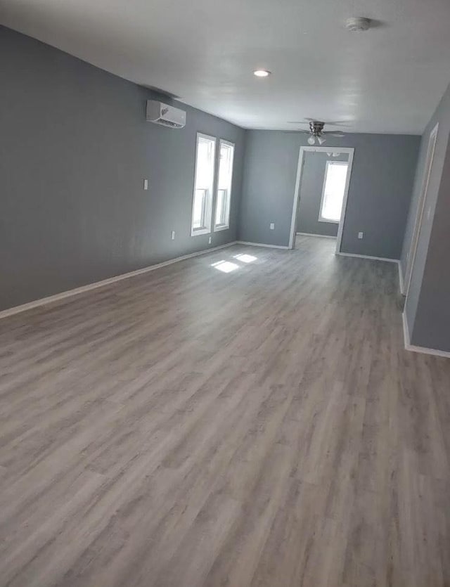 spare room featuring ceiling fan, a wall mounted air conditioner, and light wood-type flooring