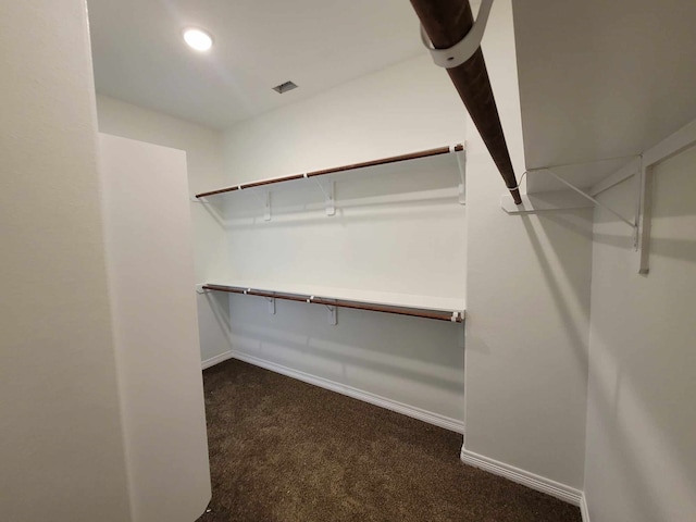 walk in closet with dark colored carpet