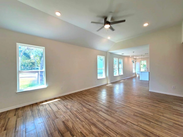 unfurnished room featuring wood-type flooring, ceiling fan with notable chandelier, and vaulted ceiling