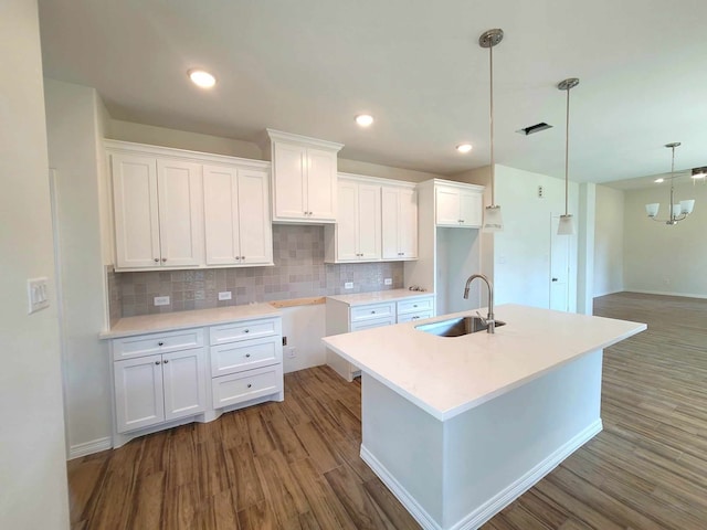 kitchen featuring sink, an island with sink, white cabinetry, pendant lighting, and dark hardwood / wood-style floors